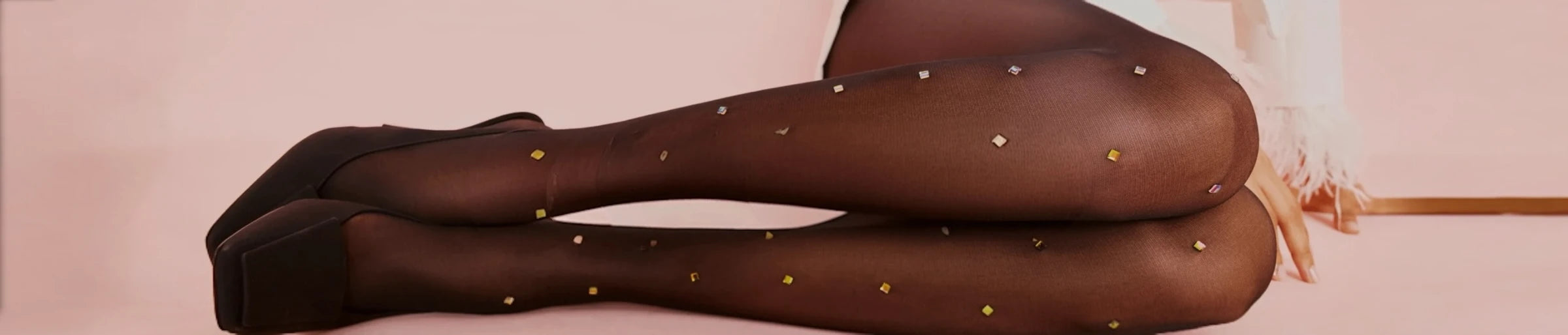 Page header image of the bottom half of the legs of a woman wearing sheer black tights with gold coloured crystals