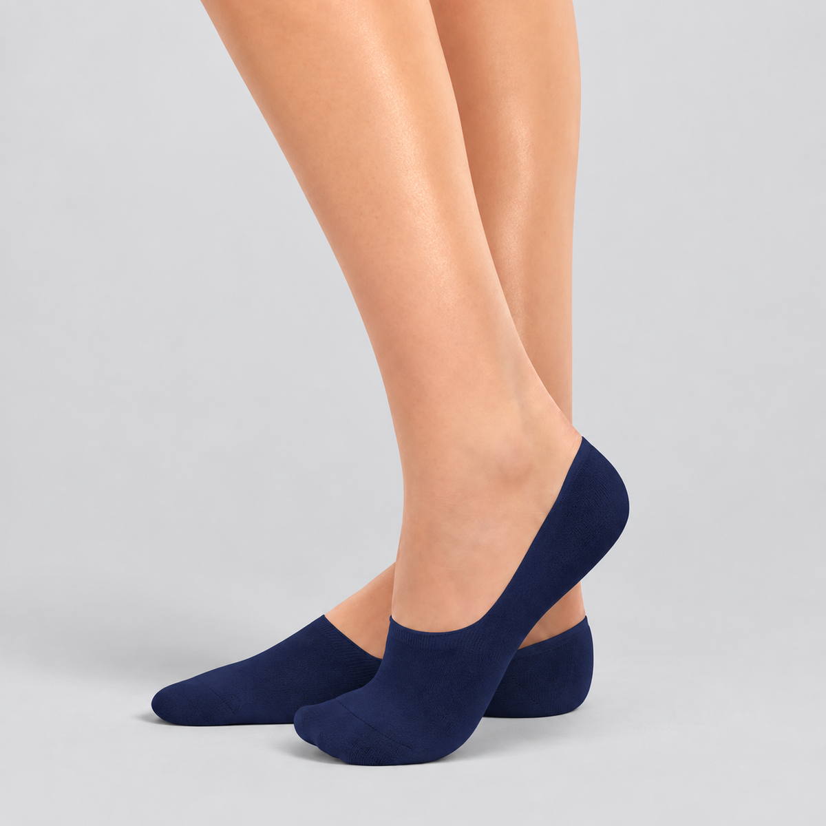 Person wearing navy bamboo no-show socks on a white background