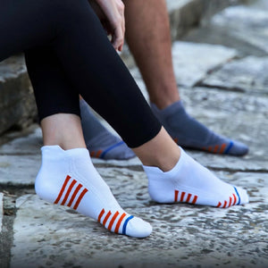A couple sitting on a stone step both wearing sneaker socks