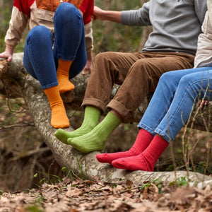Three people in a forrest wearing bright coloured eco-friendly cotton socks