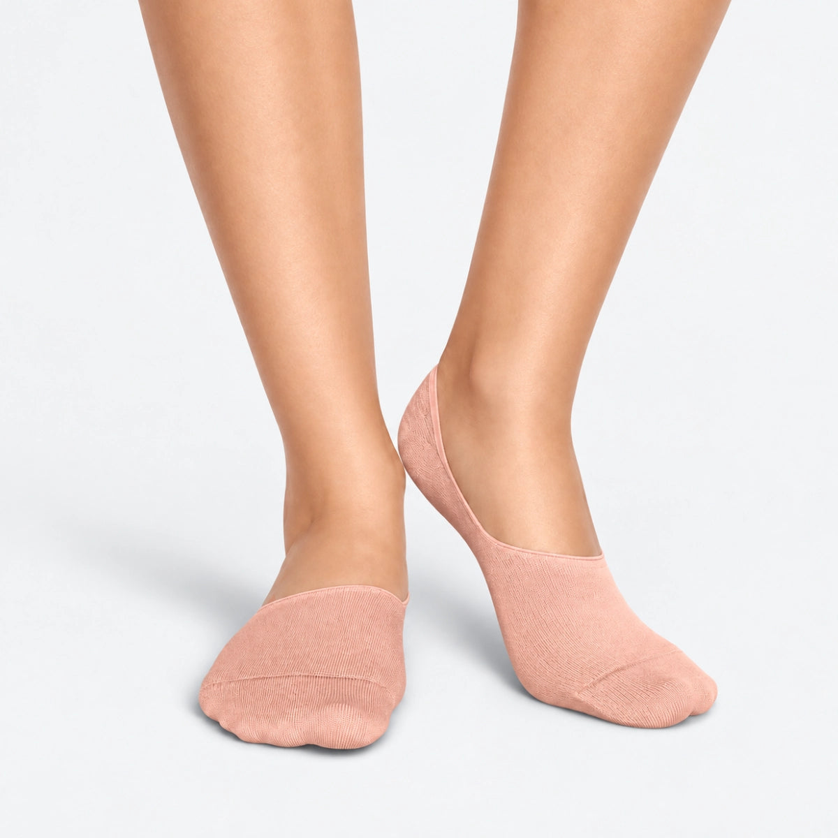 Person wearing salmon bamboo no-show socks on a light grey background