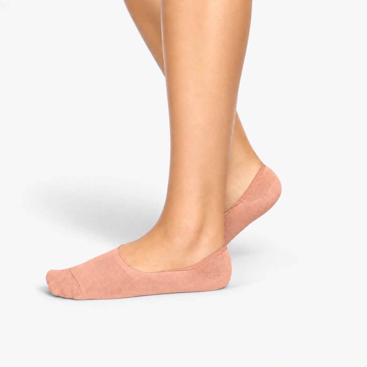 Person wearing salmon bamboo no-show socks on a light grey background