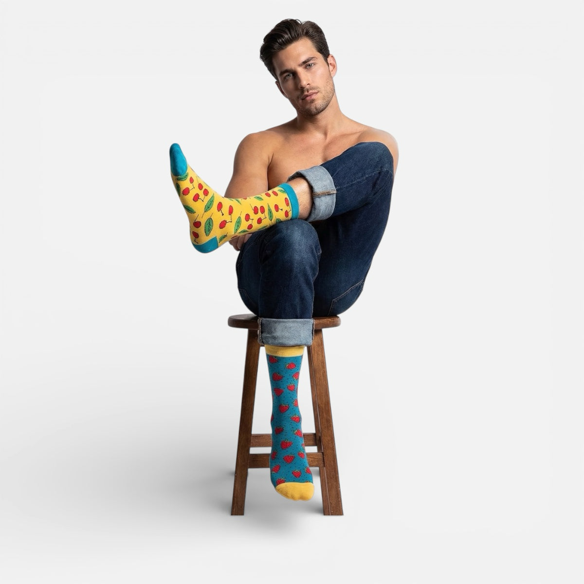 Man sitting on a stool wearing cherry themed socks with a plain background