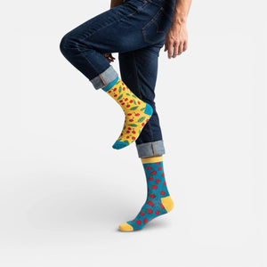 Person wearing cherry themed mismatched socks with rolled-up jeans on a white background