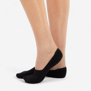 Person wearing black bamboo no-show socks on white background