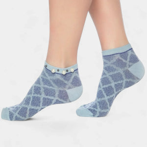 A woman wearing blue checked ankle socks finished with pearls around the cuff