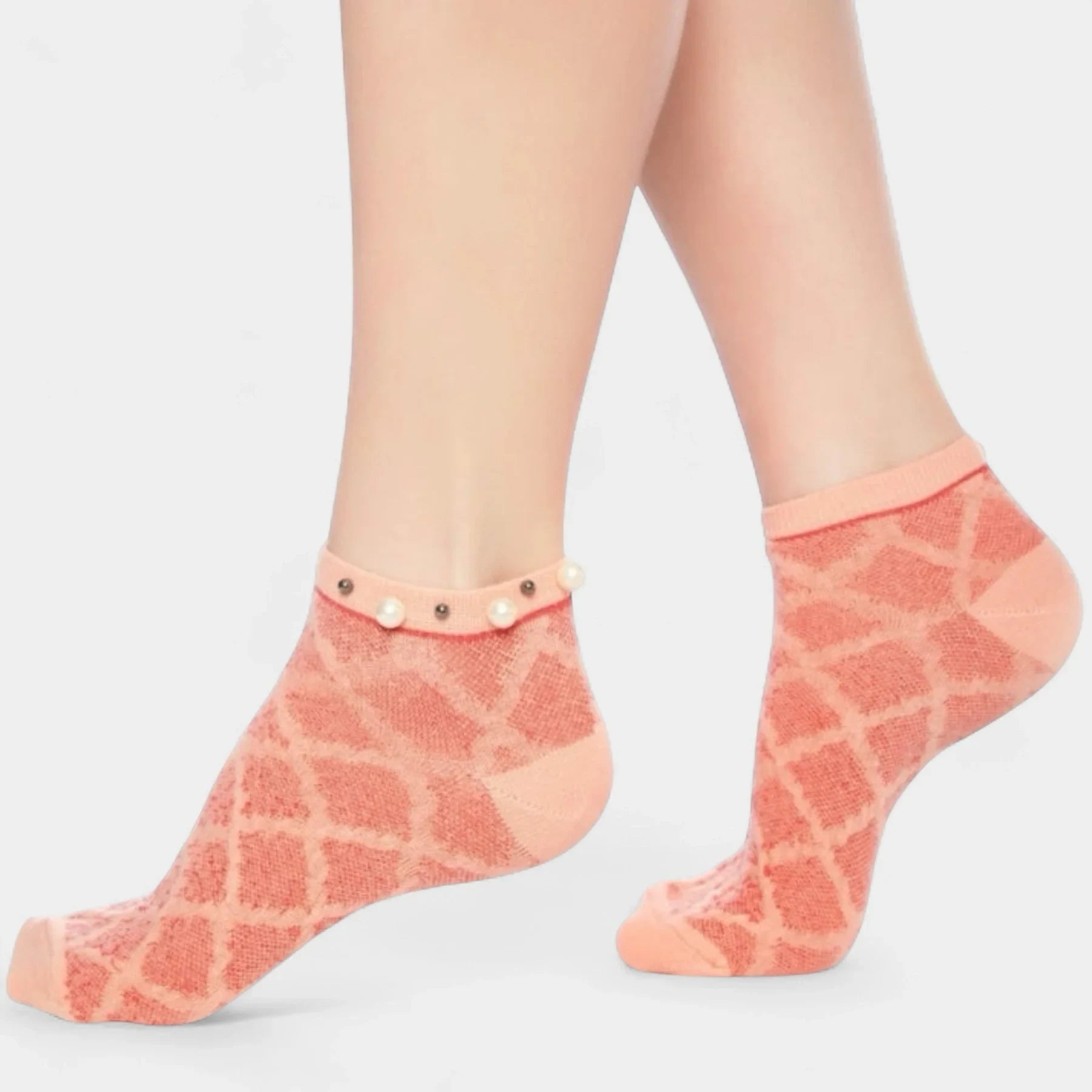A woman wearing orange checked ankle socks finished with pearls around the cuff