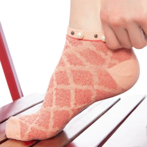 A woman wearing orange checked ankle socks finished with pearls around the cuff