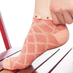 A woman wearing orange checked ankle socks finished with pearls around the cuff