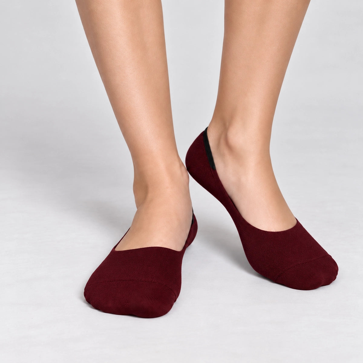 Person wearing burgundy bamboo no-show socks on a white background