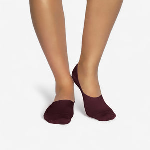Person wearing burgundy bamboo no-show socks on a white background