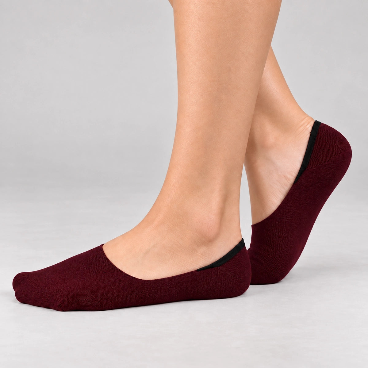 Person wearing burgundy bamboo no-show socks on a white background