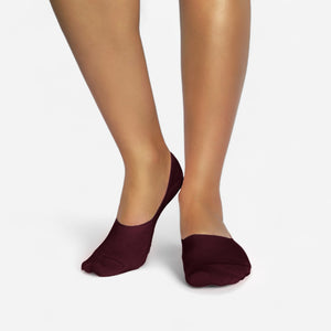Person wearing burgundy bamboo no-show socks on a white background