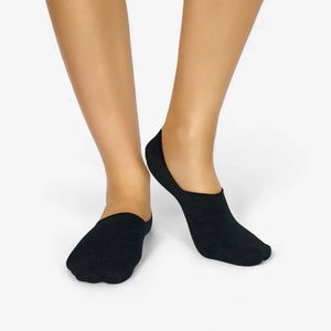 Person wearing black bamboo no-show socks on white background