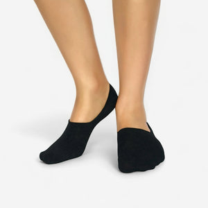 Person wearing black bamboo no-show socks on white background