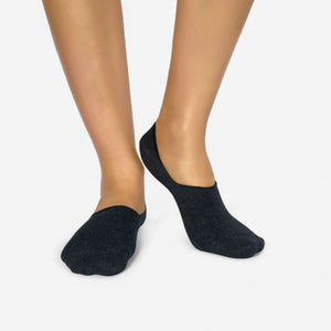 Grey no-show socks worn by a person on a light grey background