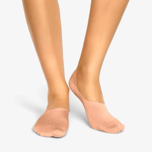 Person wearing salmon bamboo no-show socks on a light grey background