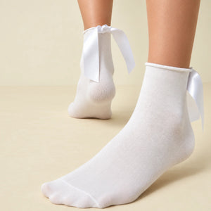 Person wearing white quarter length socks with delicate bow accent
