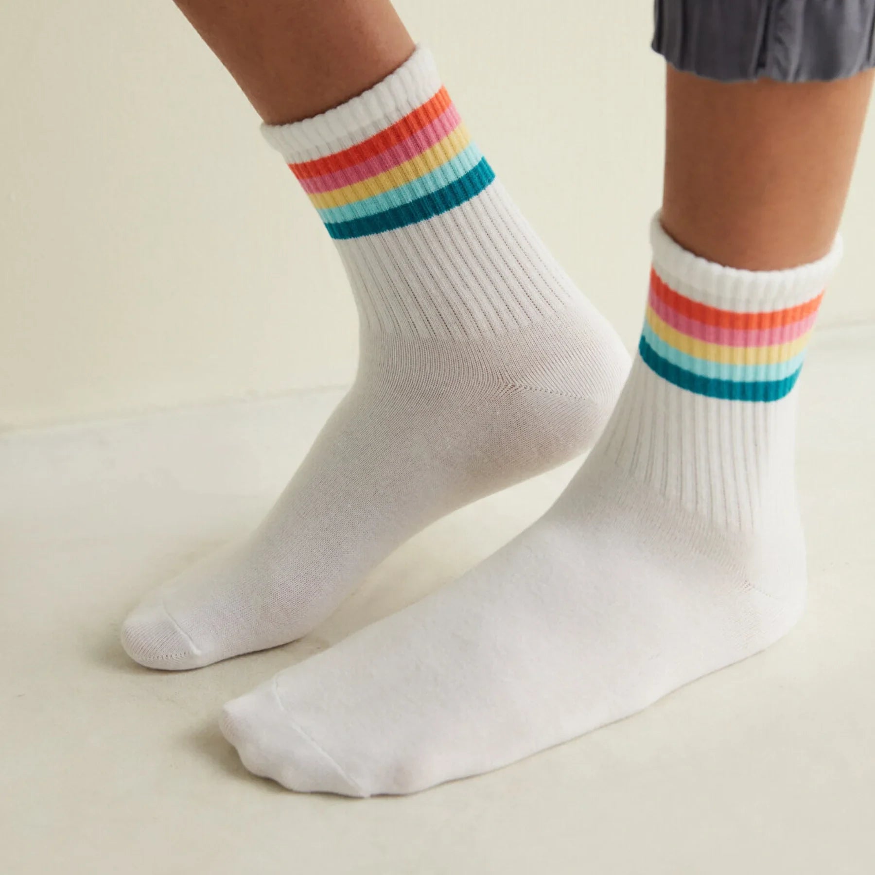 Person wearing white tennis socks with multi coloured cuff stripes