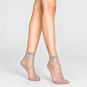 Person wearing sheer grey ankle socks with silver dots