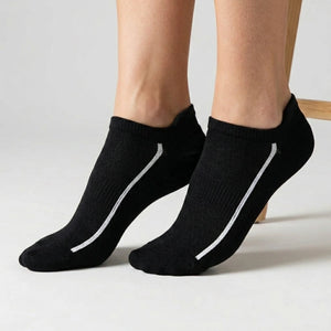 Black ankle socks with white stripes worn by a person on a light background