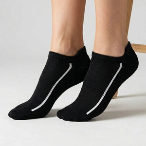 Black ankle socks with white stripes worn by a person on a light background