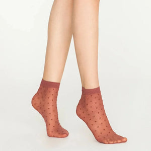Woman wearing sheer cinnamon ankle socks with sparkling gold dots on white background