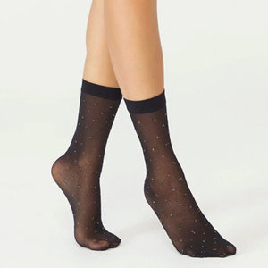 Black sheer ankle socks with criss cross pattern worn by a person on a white background, silver metallic detail elevates the design