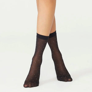Black sheer ankle socks with criss cross pattern worn by a person on a white background, silver metallic detail elevates the design