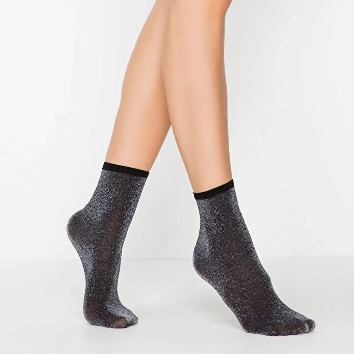 Woman wearing black sparkly ankle socks with silver glitter and a ribbed cuff