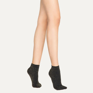 Woman wearing black and gold, sparkly ankle sock