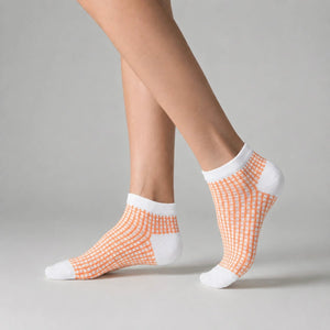 Person wearing white and apricot ankle socks against a light background