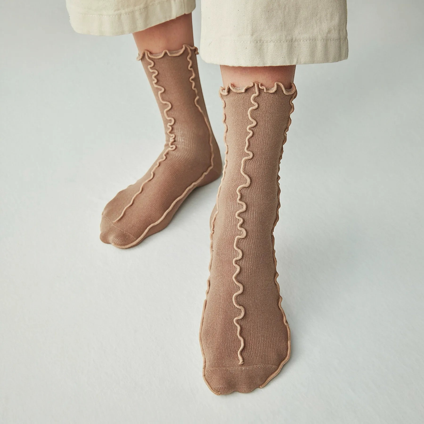 Person wearing coffee coloured, frilled socks