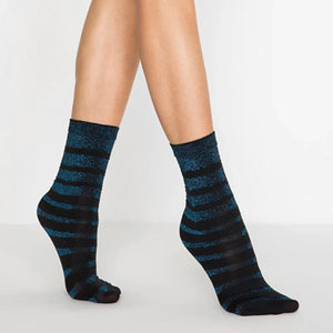 Person wearing metalic blue and black striped socks on a light grey background