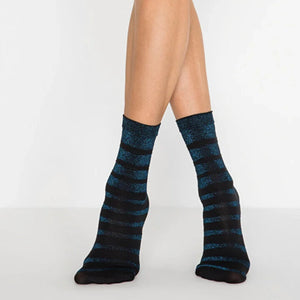 Person wearing metalic blue and black striped socks on a light grey background