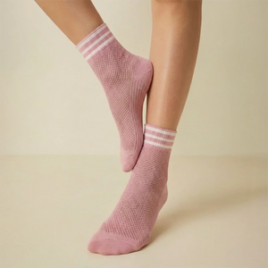 Pink open-weave socks with white striped cuff socks worn by a person on a light background