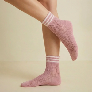 Pink open-weave socks with white striped cuff socks worn by a person on a light background