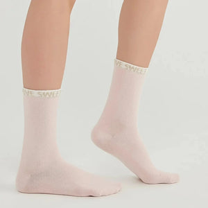 Woman wearing pale pink crew socks with 'Love Sweet' slogan around the cuff