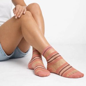 Sheer coral striped socks worn by a person on a white background