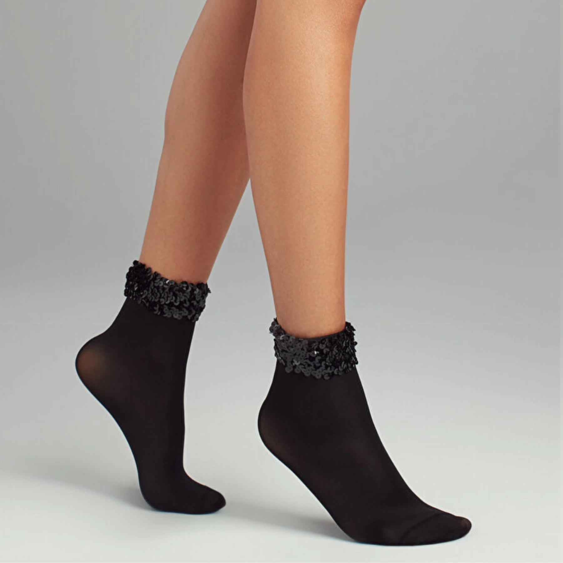 Woman wearing sheer quarter length socks with sequinned cuff