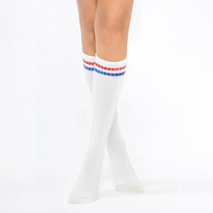 Woman wearing white knee-high socks with red and blue stripe on the cuff and the slogan 'you are not alone'