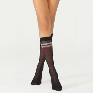 person wearing sheer black knee high socks with multicoloured striped cuff