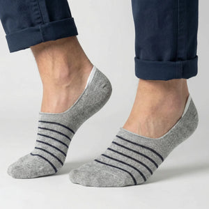 Grey no-show socks with black stripes worn with rolled-up navy pants on a light grey background