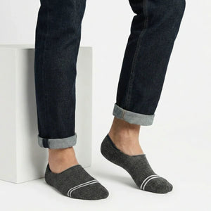 Person wearing dark grey no-show socks with white stripes on a light background