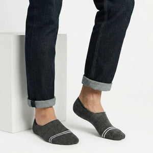 Person wearing dark grey no-show socks with white stripes on a light background