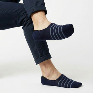 Navy with lighter blue stripe no-show socks worn with rolled-up dark pants on a light background