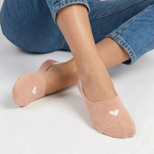 Person wearing a beige no-show sock with a cream heart design and jeans on a light grey background
