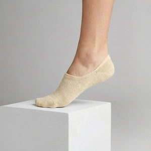 Beige no-show sock with gold sparkly yarn and open weave design for comfort worn by a person on a light grey background