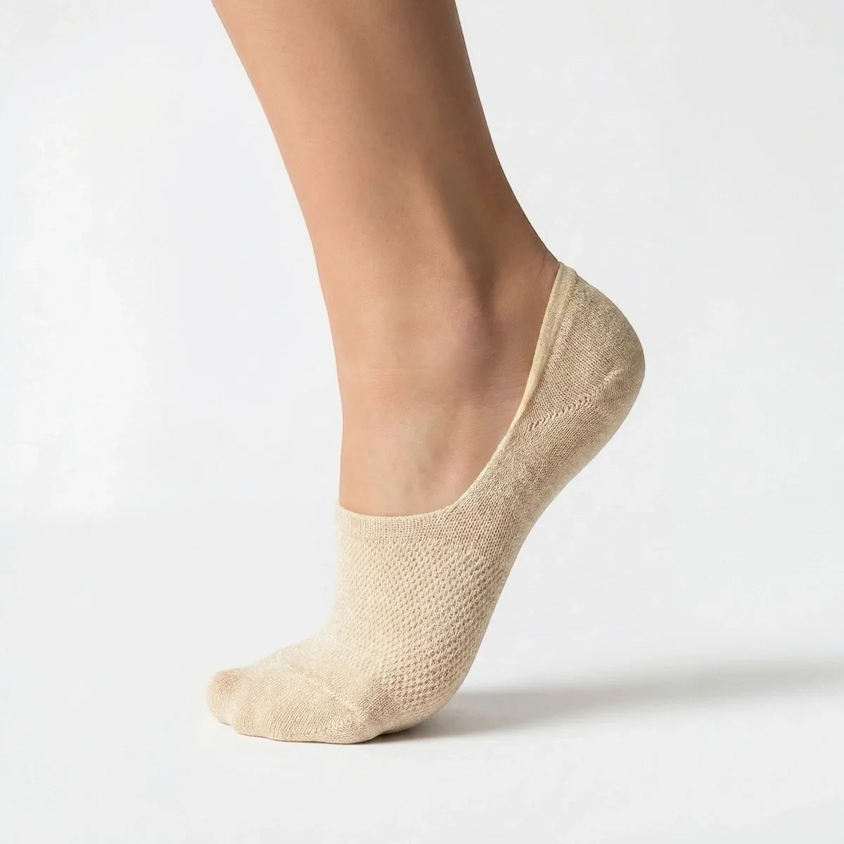 Beige no-show sock with gold sparkly yarn and open weave design for comfort worn by a person on a light grey background