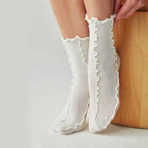 Person wearing ivory coloured, frilled socks